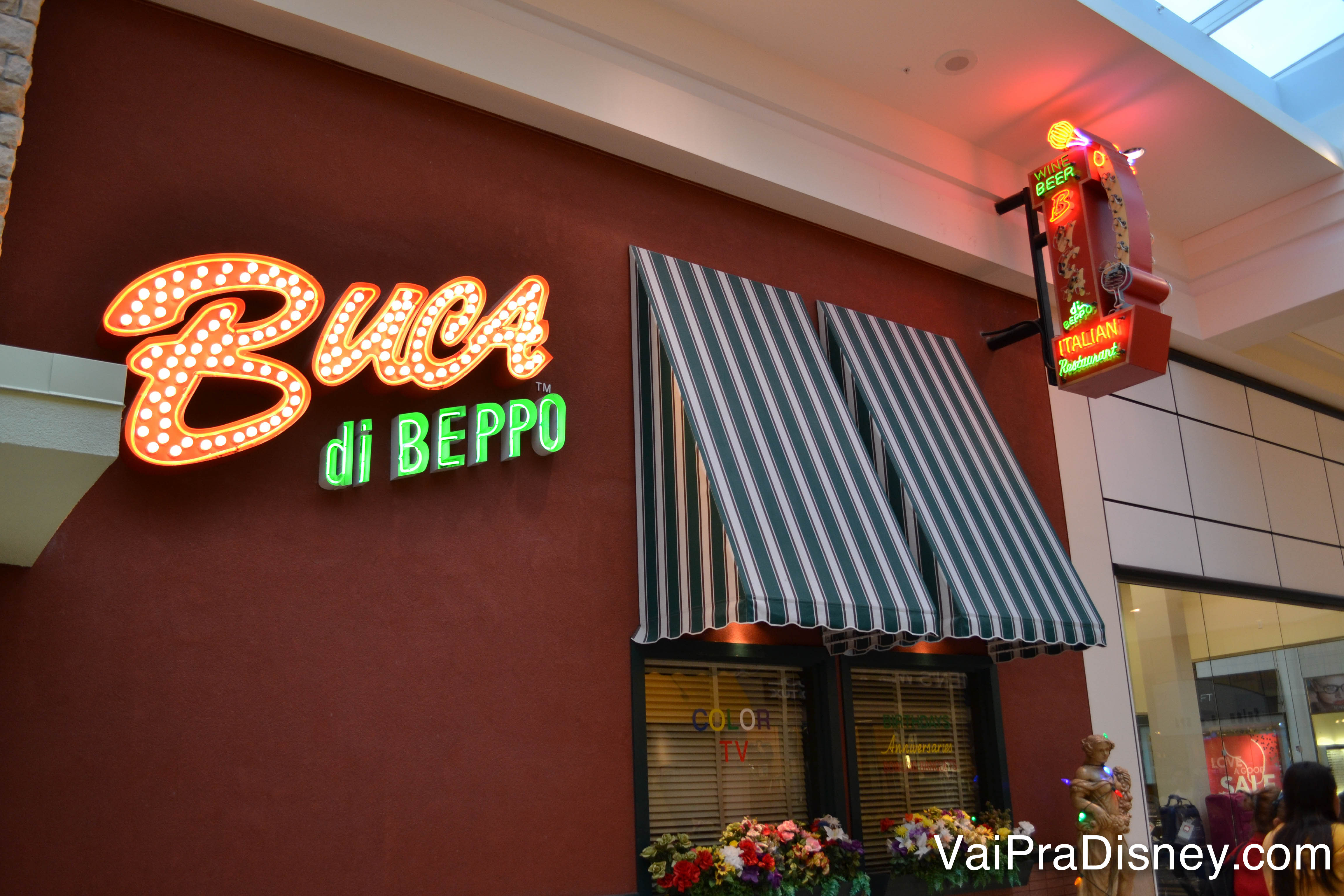 Foto da entrada do Buca di Beppo no Florida Mall, com o nome do restaurante em neon e toldos listrados em azul e branco 