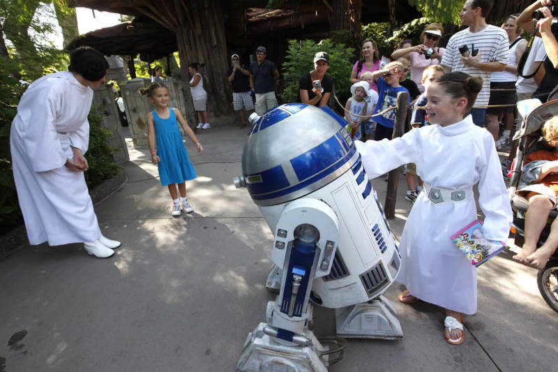 Famoso robozinho R2D2 tirando foto e brincando com uma criança fantasiada de princesa Leia