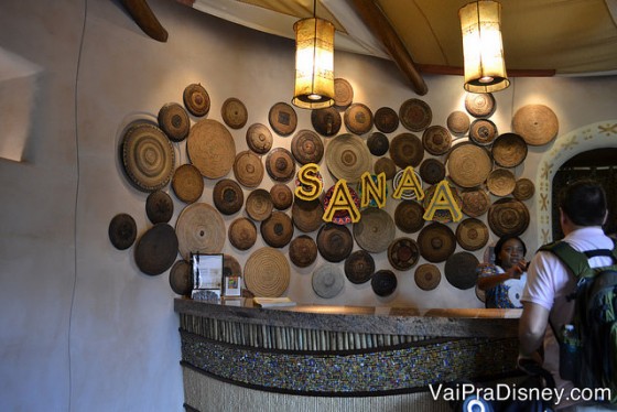 Recepção do Sanaa, com as esferas de madeira decorativas atrás e o nome do local em amarelo 
