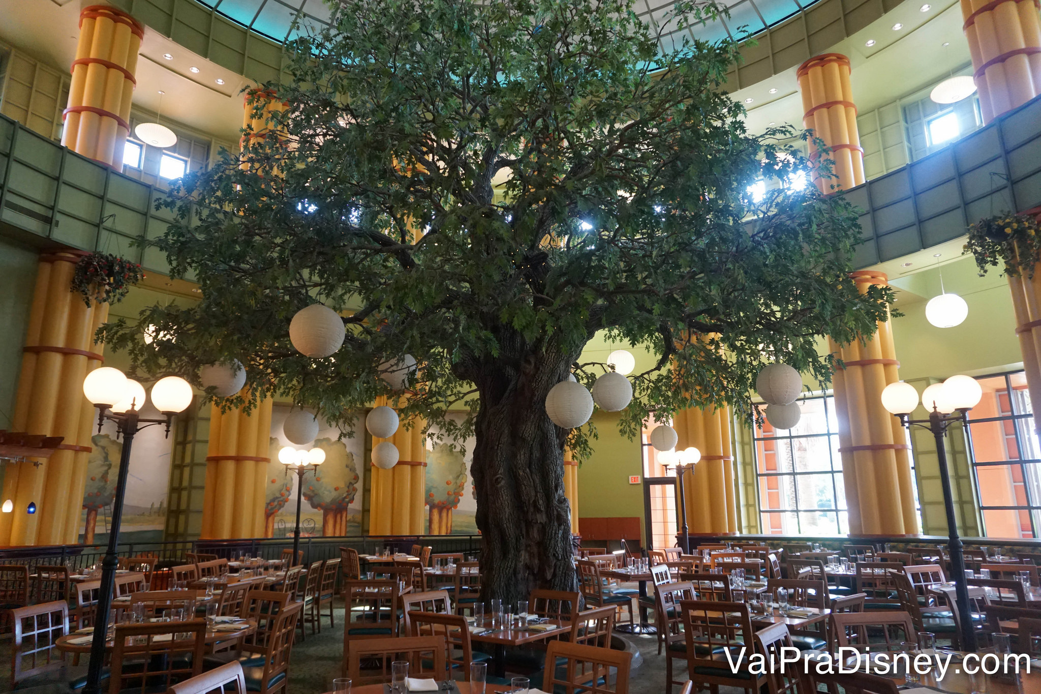 O ambiente do Garden Grove, com uma árvore enorme no centro das mesas e lâmpadas redondas penduradas nela 