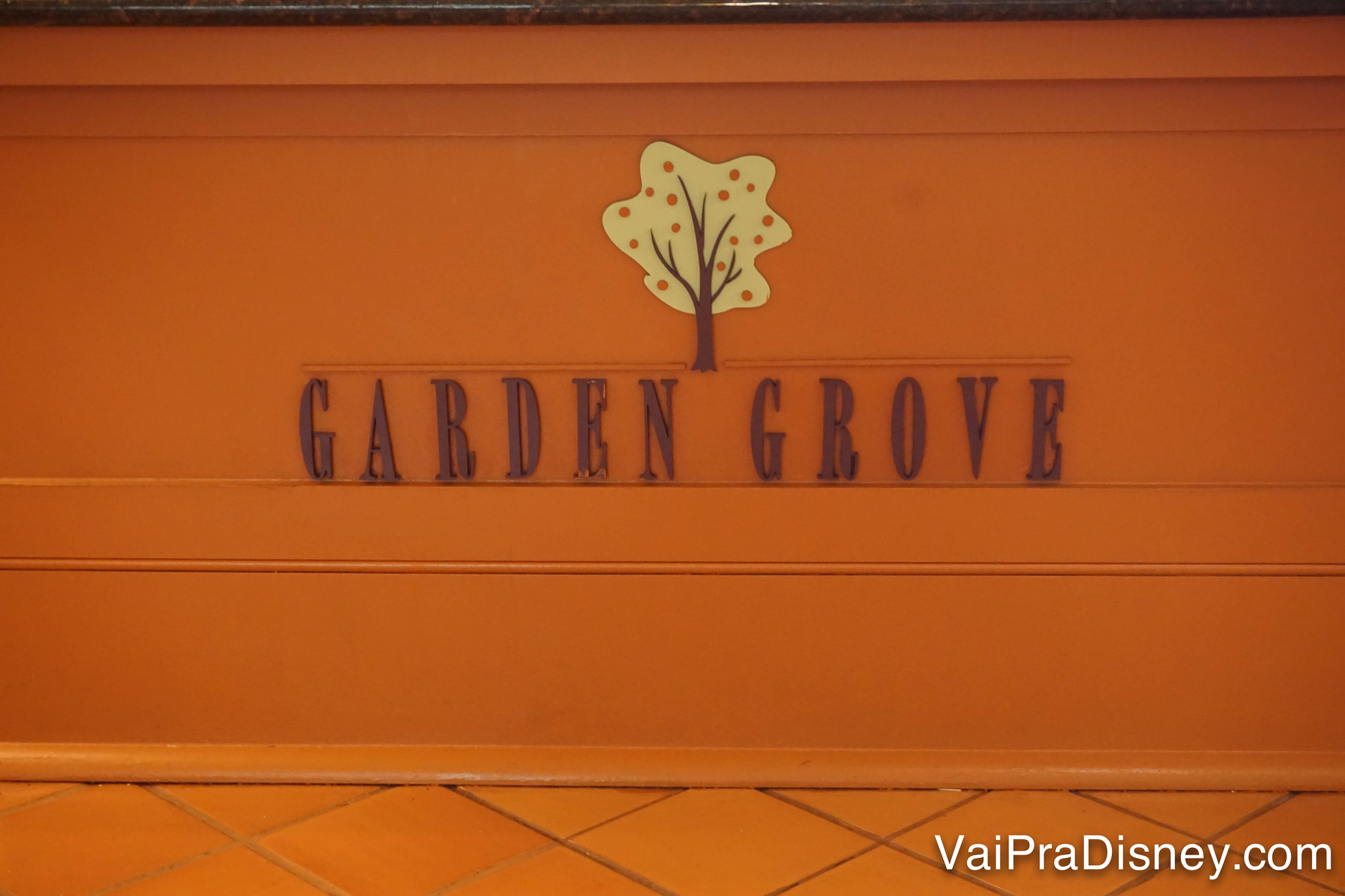 Foto da placa do Garden Grove, com fundo laranja e uma árvore, no Swan Hotel 