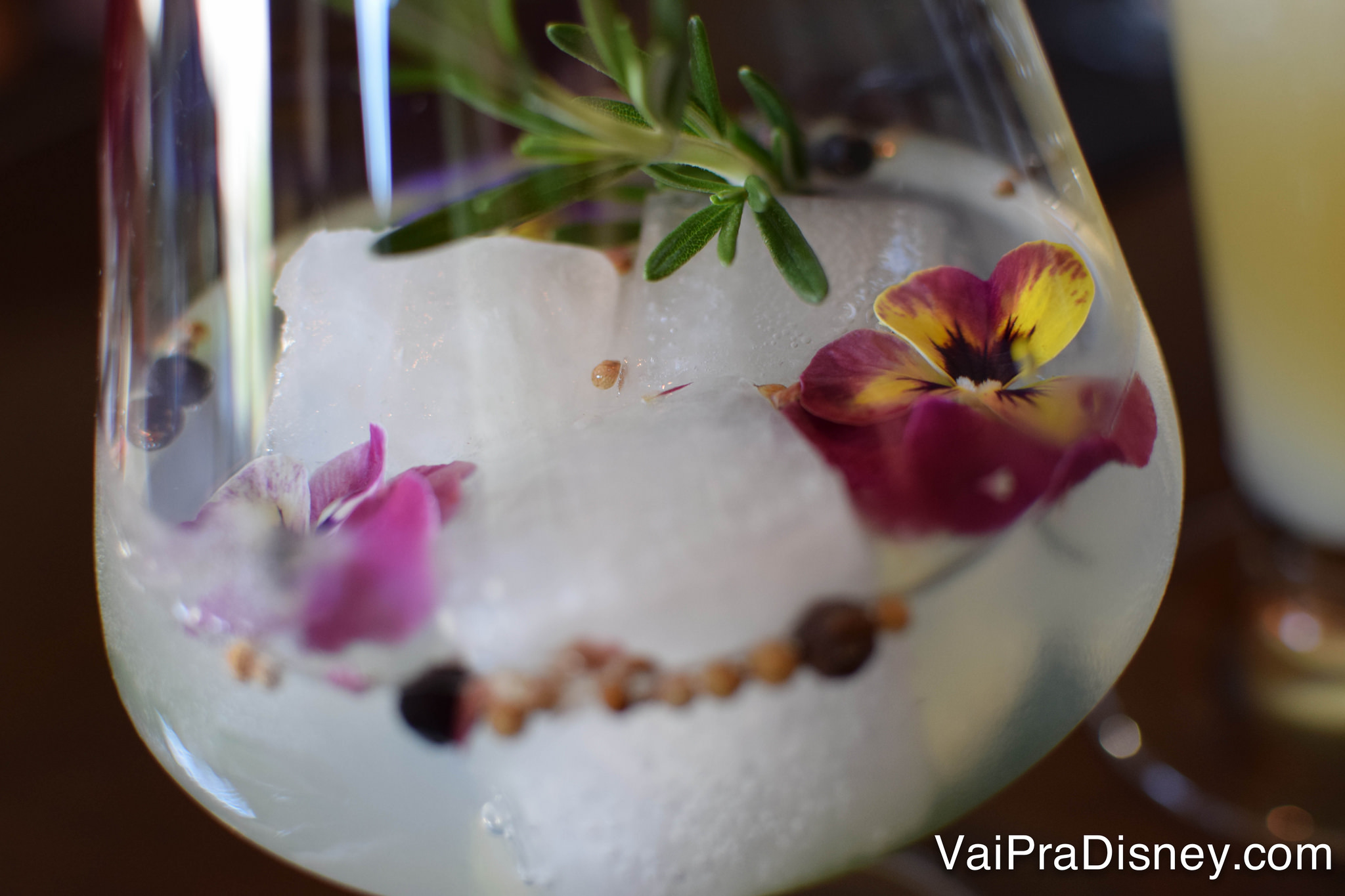 Um drinque servido com flores decorativas em uma taça arredondada 