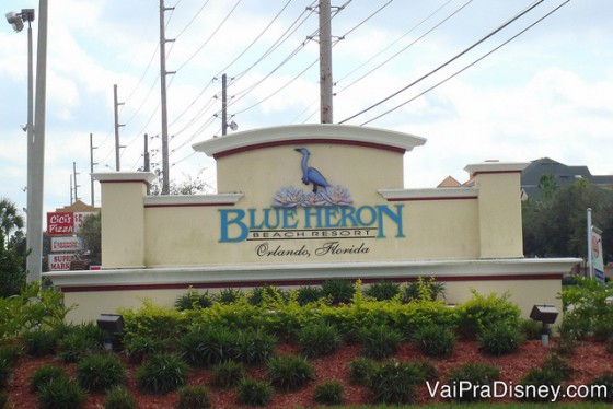 Foto da entrada do Blue Heron. Um hotel com cara de casa em Orlando. O símbolo é uma cegonha azul, com o nome do local também em azul. 
