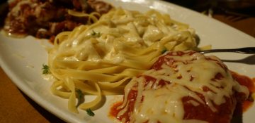 Foto da comida no prato do Olive Garden, diversas massas com queijo, molho branco e molho vermelho