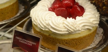 Foto da vitrine da Cheesecake Factory, mostrando o clássico cheesecake com calda de morango e chantilly