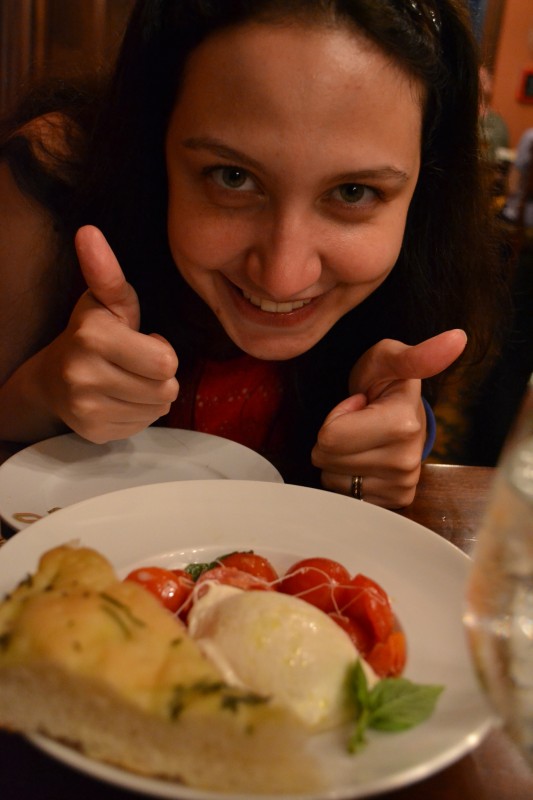 Renata fazendo joinha e uma entrada de burrata. 