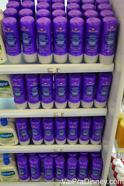 Aussie agora é encontrado não só na CVS mas em várias outras lojas. Foto de uma prateleira de farmácia com cremes da marca Aussie, com sua embalagem roxa. 