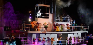 Foto do show Fantasmic no Hollywood Studios. A imagem mostra um barco no lago do parque, durante à noite, com muitos personagens dançando.