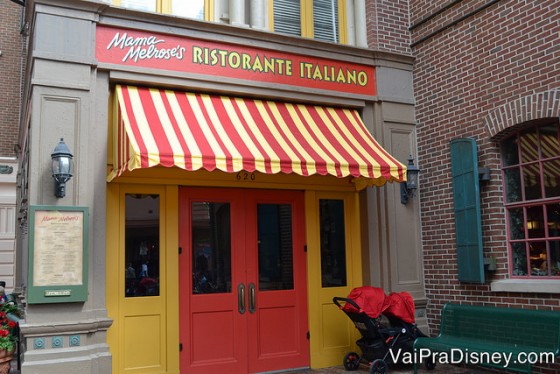 Foto da fachada do Mama Melrose's Ristorante Iitaliano. A porta é vermelha, a frente é pintada de amarelo, o toldo é listrado em vermelho e branco e a placa também é amarela e vermelha. 