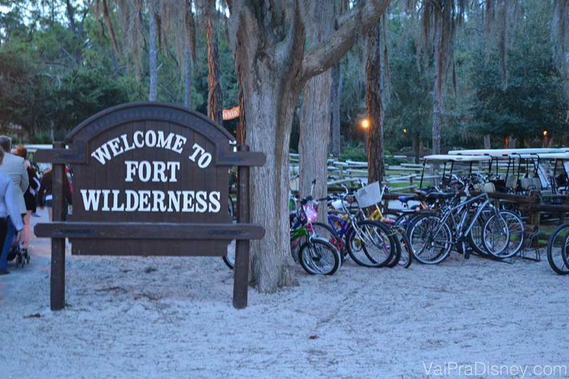 Foto da placa que diz "Welcome to Fort Wilderness" no hotel, com árvores ao fundo e bicicletas para alugar ao lado 