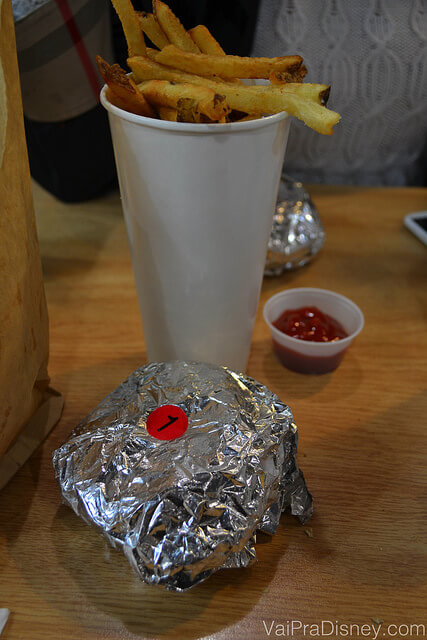Batatinha frita que vem junto com o sanduíche, embalado no papel alumínio e o ketchup ao lado 