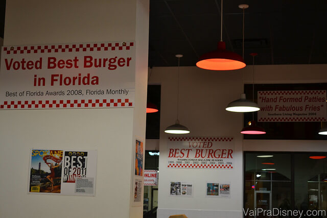 Várias placas com guias, jornais e revistas que recomendam o Five Guys no restaurante de Orlando 