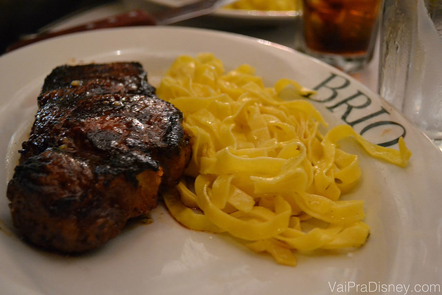 Prato com uma carne grelhada e macarrão acompanhando 