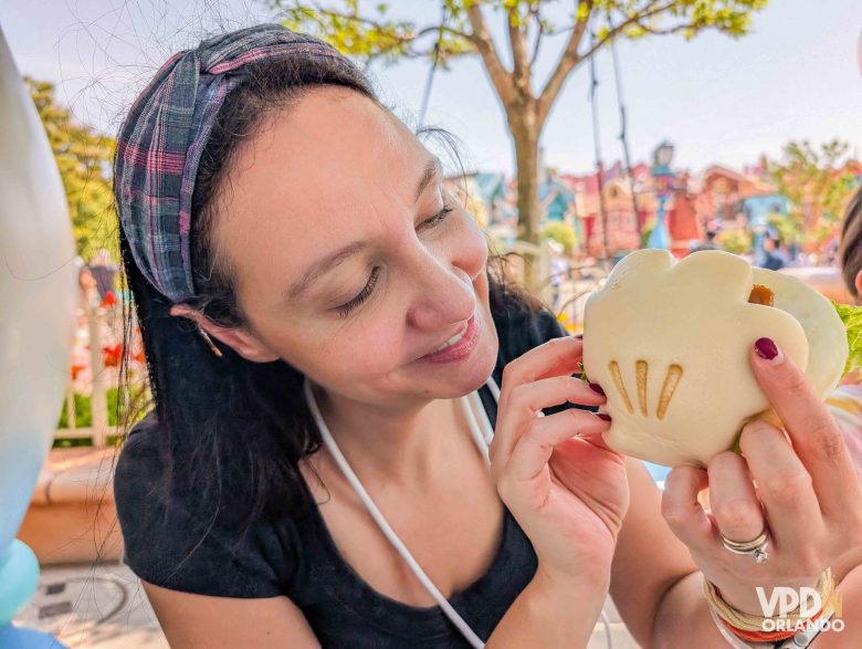 A Renata está segurando um bao em formato de luva do Mickey.