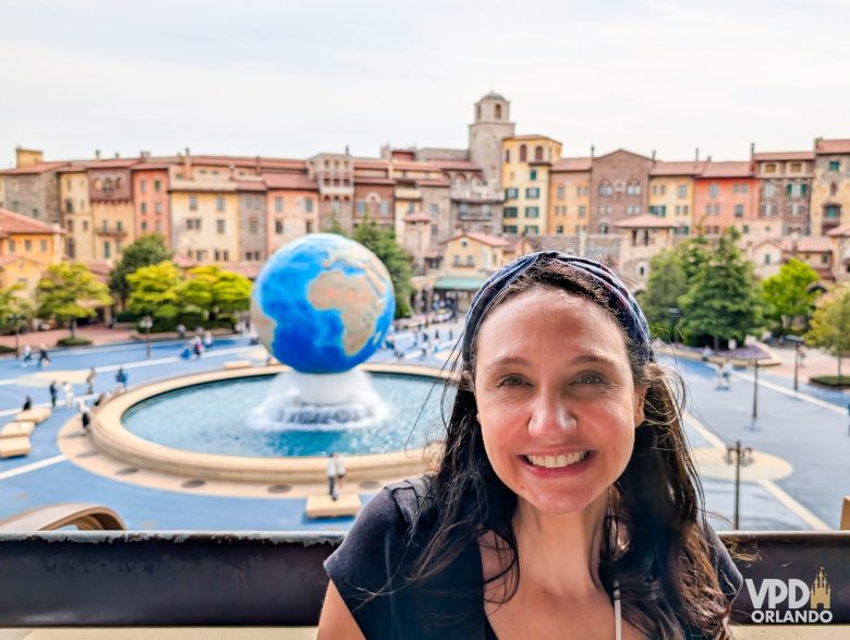 A Renata está sorrindo em frente à fonte com o globo do Tokyo DisneySea
