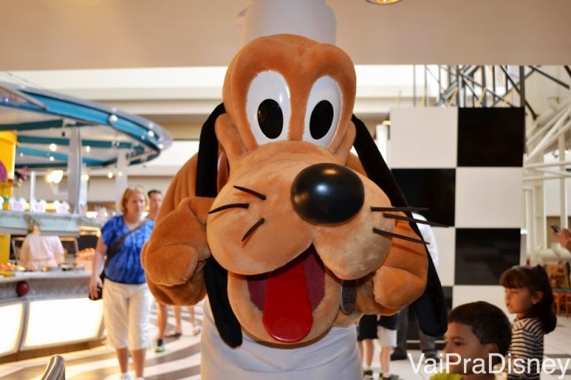 Foto do Pluto com roupa de chef posando para a câmera em uma refeição com personagens 