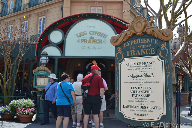 Imagem da fila na entrada do Chefs de France, com visitantes esperando para entrar ao lado da placa do restaurante. 