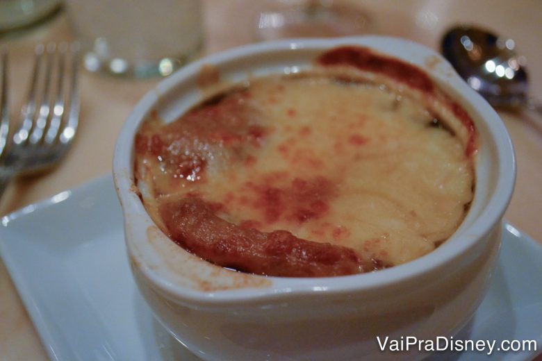 Foto do prato no Be our Guest, com a sopa de cebola gratinada em cima, servida no almoço e no jantar.