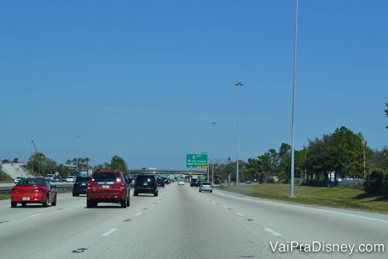 Dirigir em Orlando é tranquilo e mais gostoso do que dirigir no Brasil.  Foto da rodovia em Orlando, com diversos carros e o céu bem azul ao fundo. 