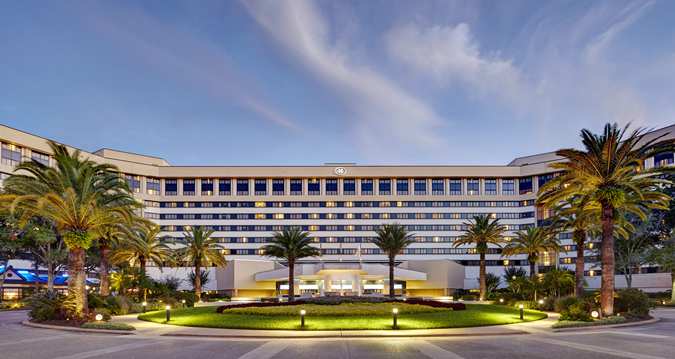 Foto da fachada do hotel Hilton Lake Buena Vista em Orlando, com palmeiras na frente e o céu azul atrás