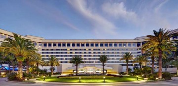 Foto da fachada do hotel Hilton Lake Buena Vista em Orlando, com palmeiras na frente e o céu azul atrás