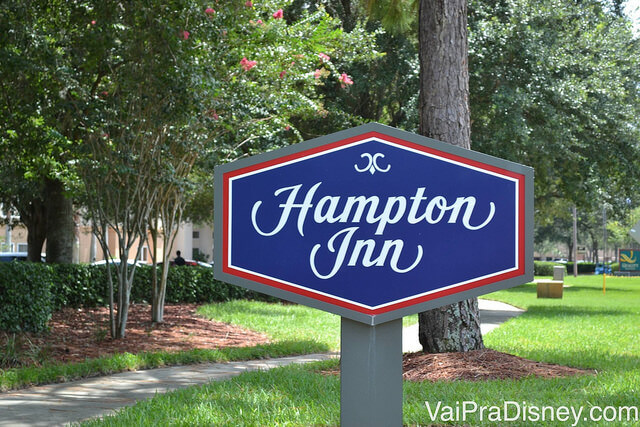 Foto da placa do hotel Hampton Inn Lake Buena Vista, que tem "Hampton Inn" escrito em branco sobre um fundo azul e bordas vermelhas