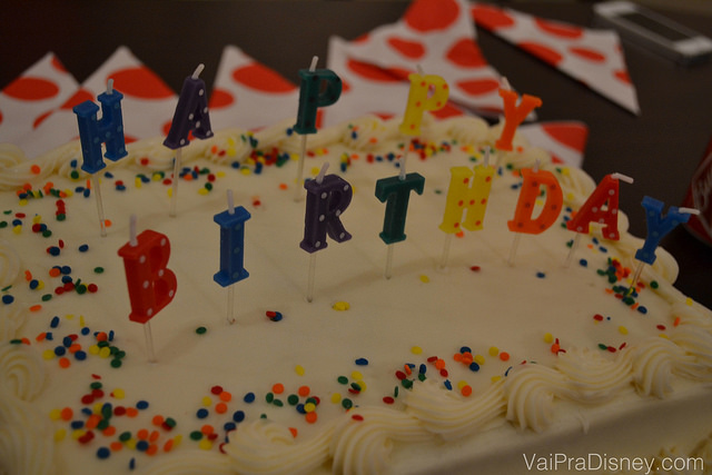 Foto de um bolo de aniversário com velas soletrando "Happy Birthday" 