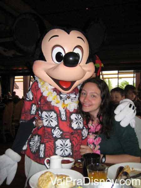 Foto da Renata abraçada com o Mickey havaiano (de camisa florida e colar) no Ohana