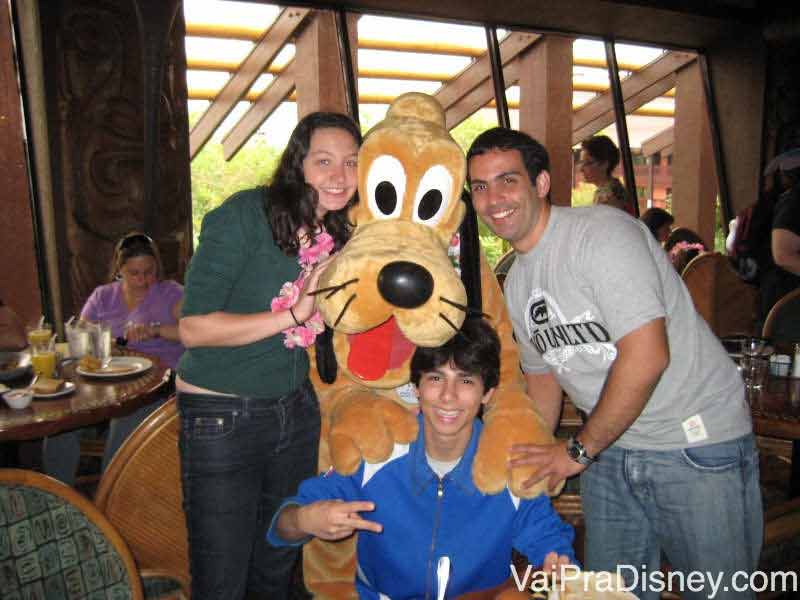 Foto da Renata de colar havaiano, com dois amigos e o Pluto, no café da manhã do Ohana 