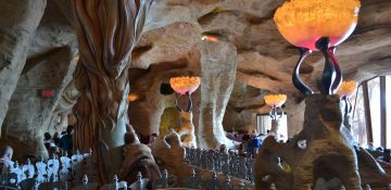 Foto do interior do Mythos, que imita uma caverna e tem lustres alaranjados.