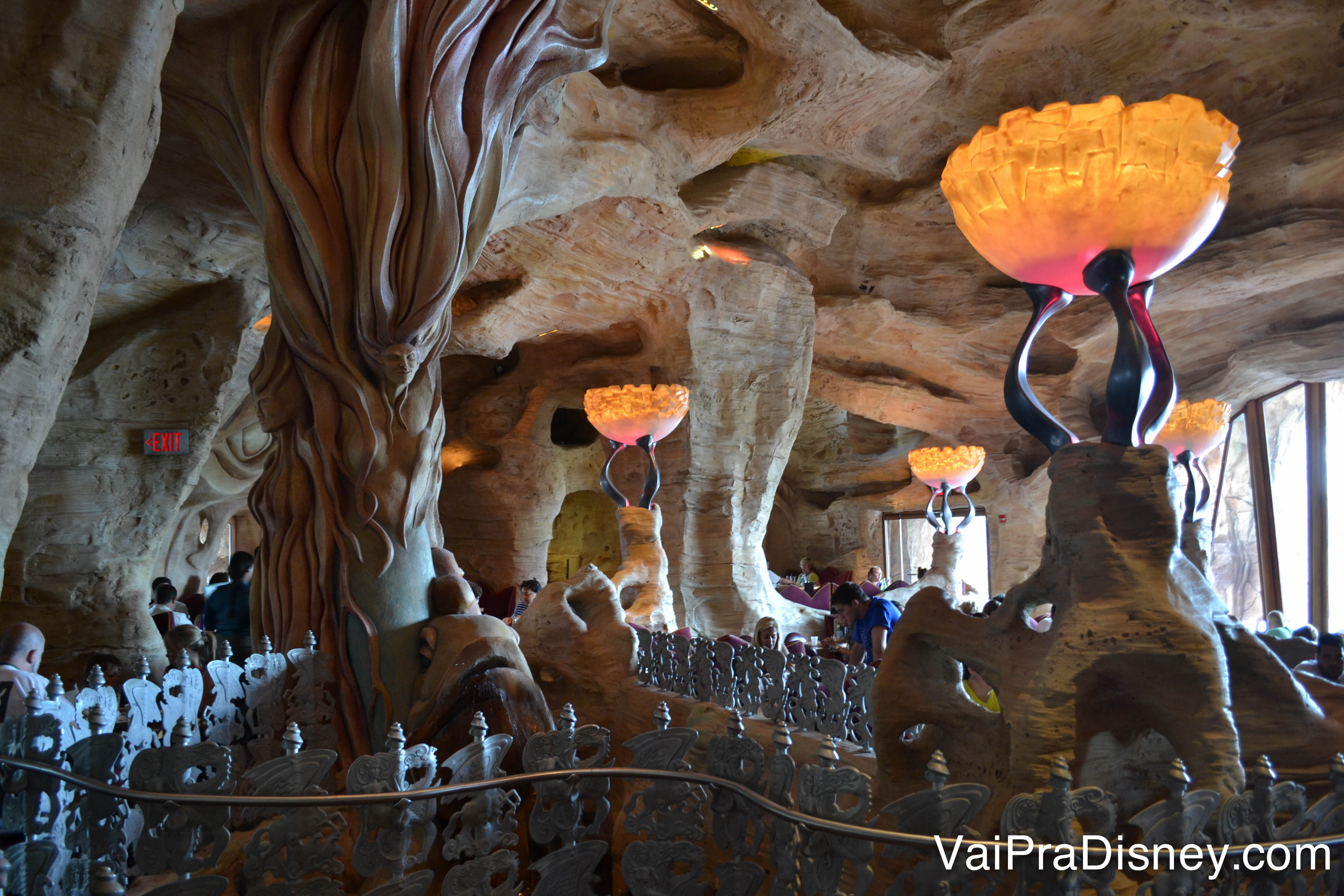 Foto do interior do Mythos, que imita uma caverna subaquática e tem lustres alaranjados. 