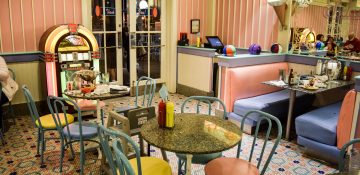 Foto do interior da lanchonete Beaches and Cream, com tema vintage e decoração em rosa, amarelo e azul