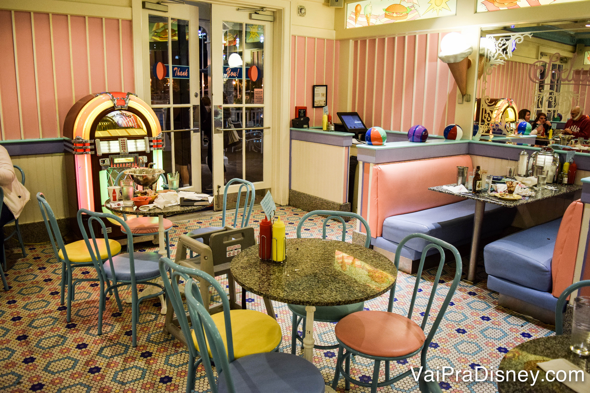 Foto do interior da lanchonete Beaches and Cream, com tema vintage e decoração em rosa, amarelo e azul 