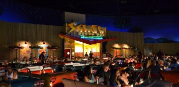 Foto do Sci-Fi Dine in Theater, o restaurante drive-in da Disney, com diversos carros antigos estacionados na frente e os visitantes dentro.