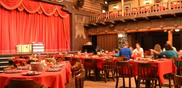 Foto do palco e das mesas durante o Hoop-Dee-Doo Musical Revue, tudo decorado em estilo Velho Oeste