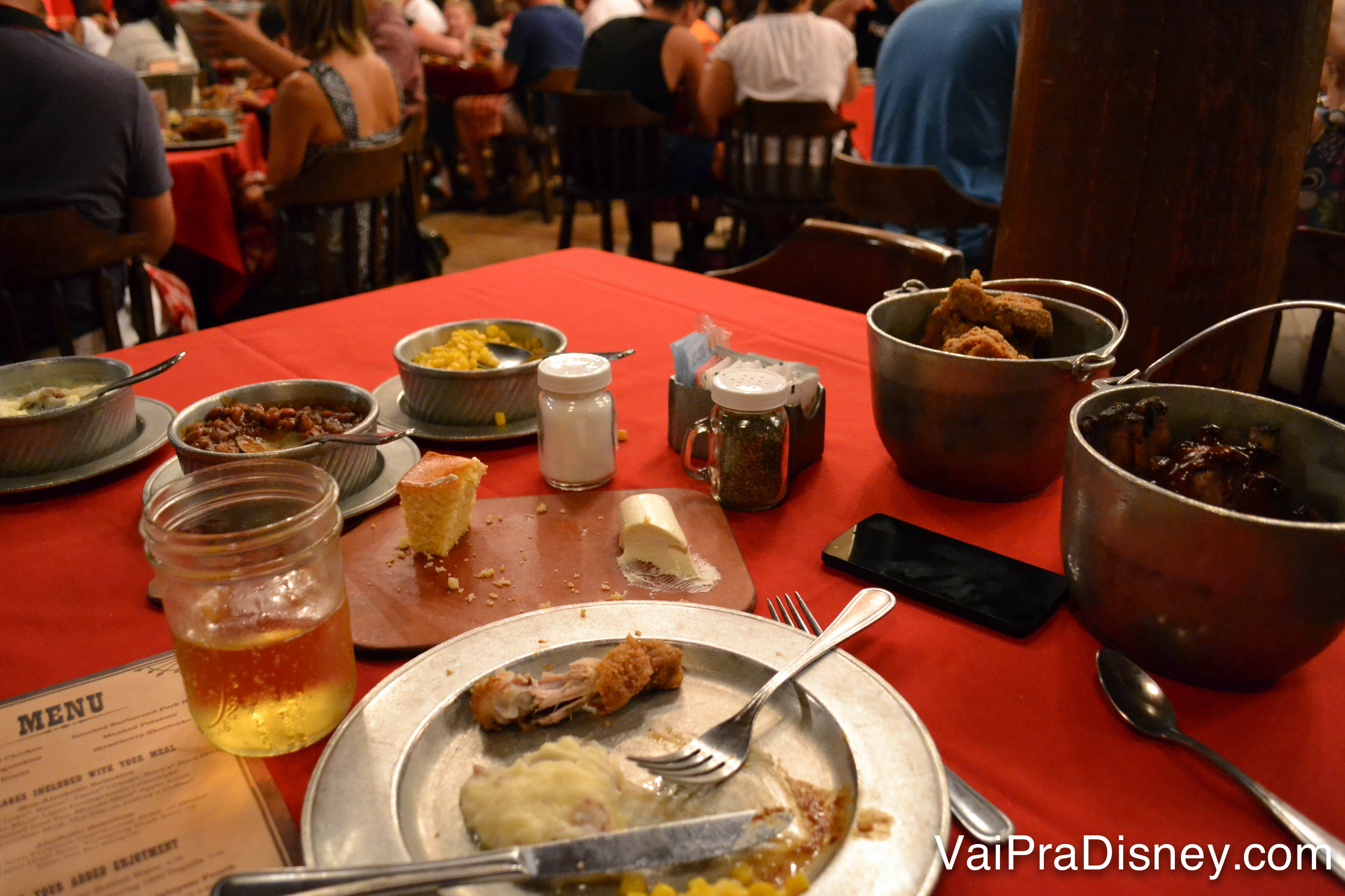 A mesa cheia de pratos, copos e ainda algumas porções de comida no fim da noite do Hoop-Dee-Doo Musical Revue