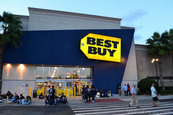 Foto da fachada da loja Best Buy que fica em frente ao shopping Mall at Millenia. Uma das mais lotadas de Orlando. Ela é pintada de azul e sua placa é amarela. 