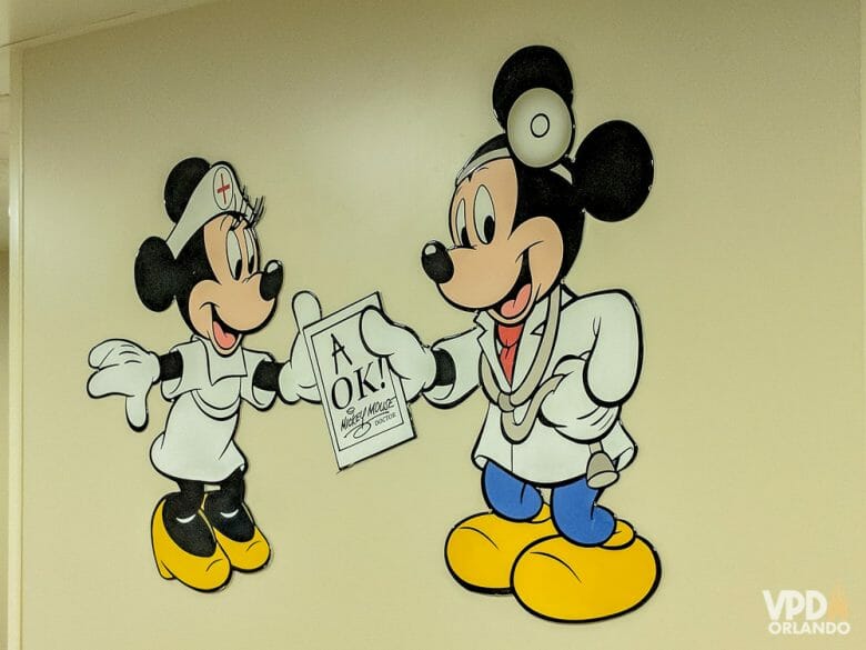 A gente espera não precisar usar, mas é sempre bom estar coberto durante a viagem e um bom seguro precisa entrar no seu pacote! Foto da central de atendimento médico da Disney, que mostra o Mickey e a Minnie com roupas de médicos. 