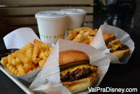 Foto dos hambúrgueres do Shake Shack, com muito queijo derretido e batatas fritas curly acompanhando. 