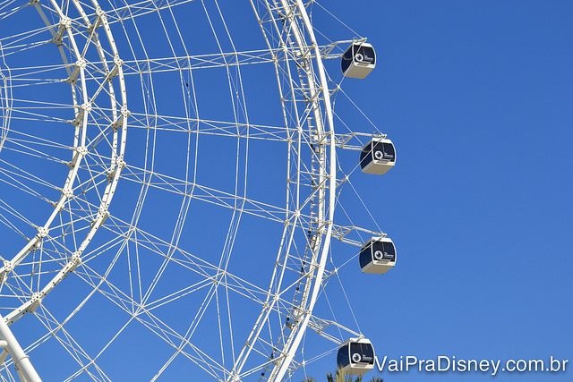 Essas são as famosas cápsulas de vidro da The Wheel. Foto da roda-gigante The Wheel mostrando metade dela, com as cápsulas de vidro onde entram os visitantes e o céu azul ao fundo. 