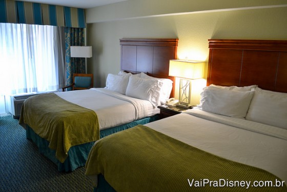 Quarto padrão do Holiday Inn com duas camas queen e um abajur entre elas 