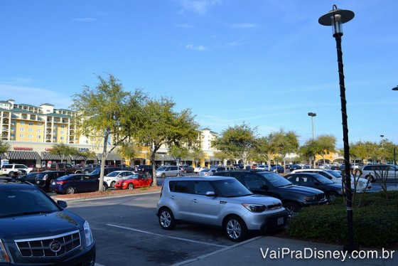 Foto do estacionamento do Lake Buena Vista Factory Stores, com diversos carros e o céu azul ao fundo 