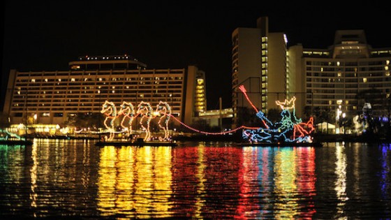 Foto do evento o Electrical Water Pageant, com barcos iluminados na água e alguns hotéis ao fundo. 