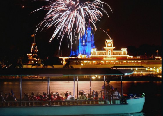 Foto dos fogos e do Magic Kingdom iluminado, além do barco, durante o Pirates & Pals Firework Voyage