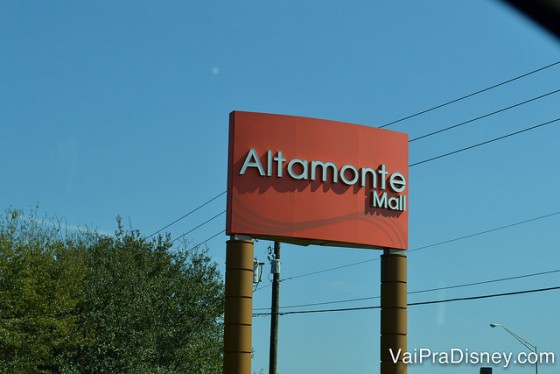 Foto da placa do Altamonte Mall, em Altamonte Springs. Ela é vermelha com letras cinza e o céu está azul ao fundo 