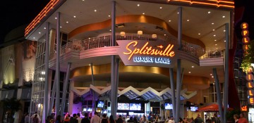 Foto do exterior do Splitsville mostrando as mesas e o letreiro iluminado do restaurante e pista de boliche através das paredes de vidro.