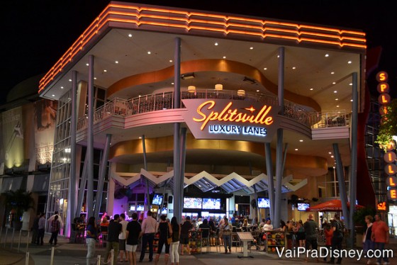 Foto do exterior do Splitsville mostrando as mesas e o letreiro iluminado do restaurante e pista de boliche através das paredes de vidro. 