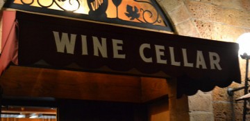 Foto da placa na pequena porta de entrada do Tutto Gusto Wine Cellar, um toldo preto apenas com as letras "Wine Cellar" em branco