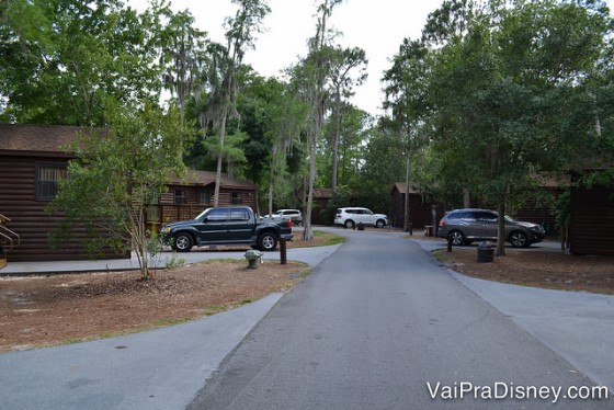 Foto das cabanas do Fort Wildeness, na floresta, com carros parados em frente. 