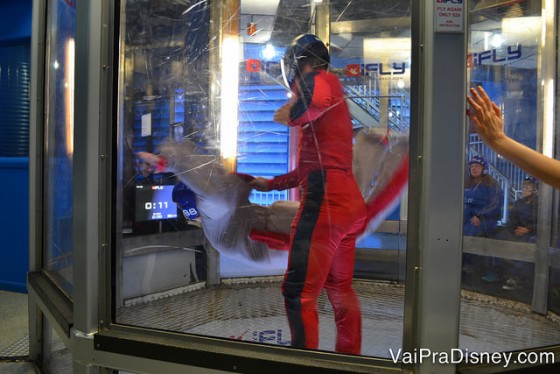 Foto de um visitante no simulador de voo com uma instrutora por perto, durante o treinamento 